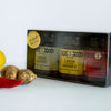 A gift box of ABC Honey featuring three jars of honey in different flavors: lemon, chilli, and ginger. There is also a lemon slice and a red chilli pepper beside the box.